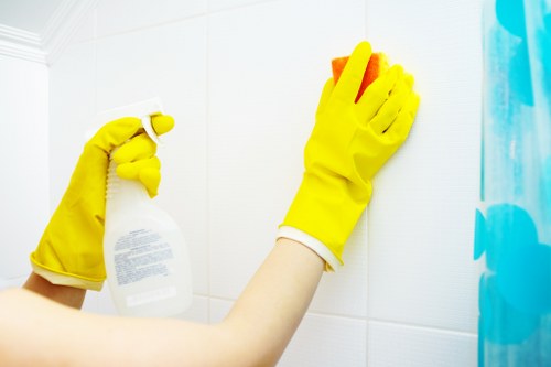A cleaner dusting and polishing kitchen surfaces in a Stockwell home